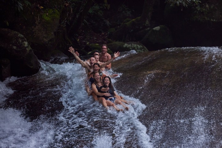 A group having fun in the Natural Rock Slide Josephine Falls