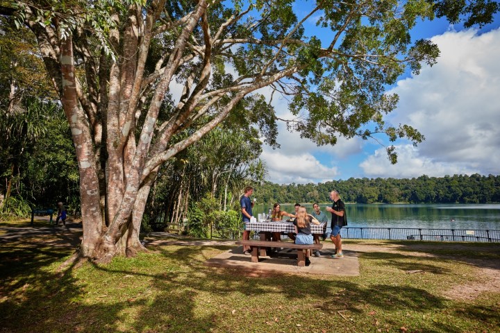 Group on a bench by a tree during Morning Tea at Lake Eacham